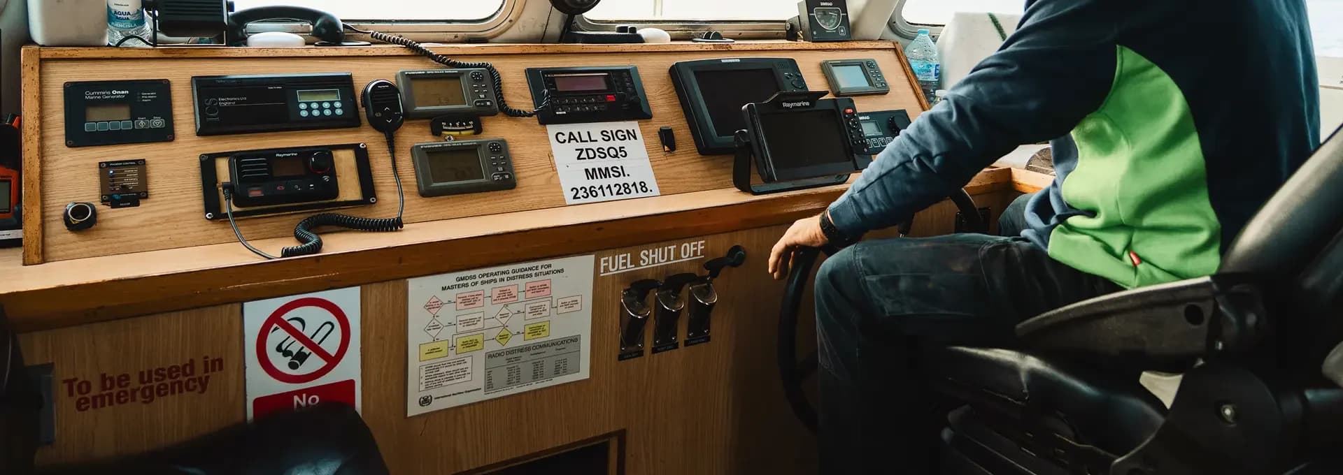 Hands at the helm beside the wheelhouse navigation equipment